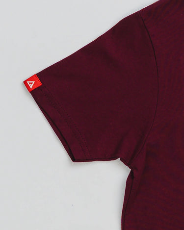 Close-up of maroon youth t-shirt sleeve with red Gracie Barra Legacy G tag.
