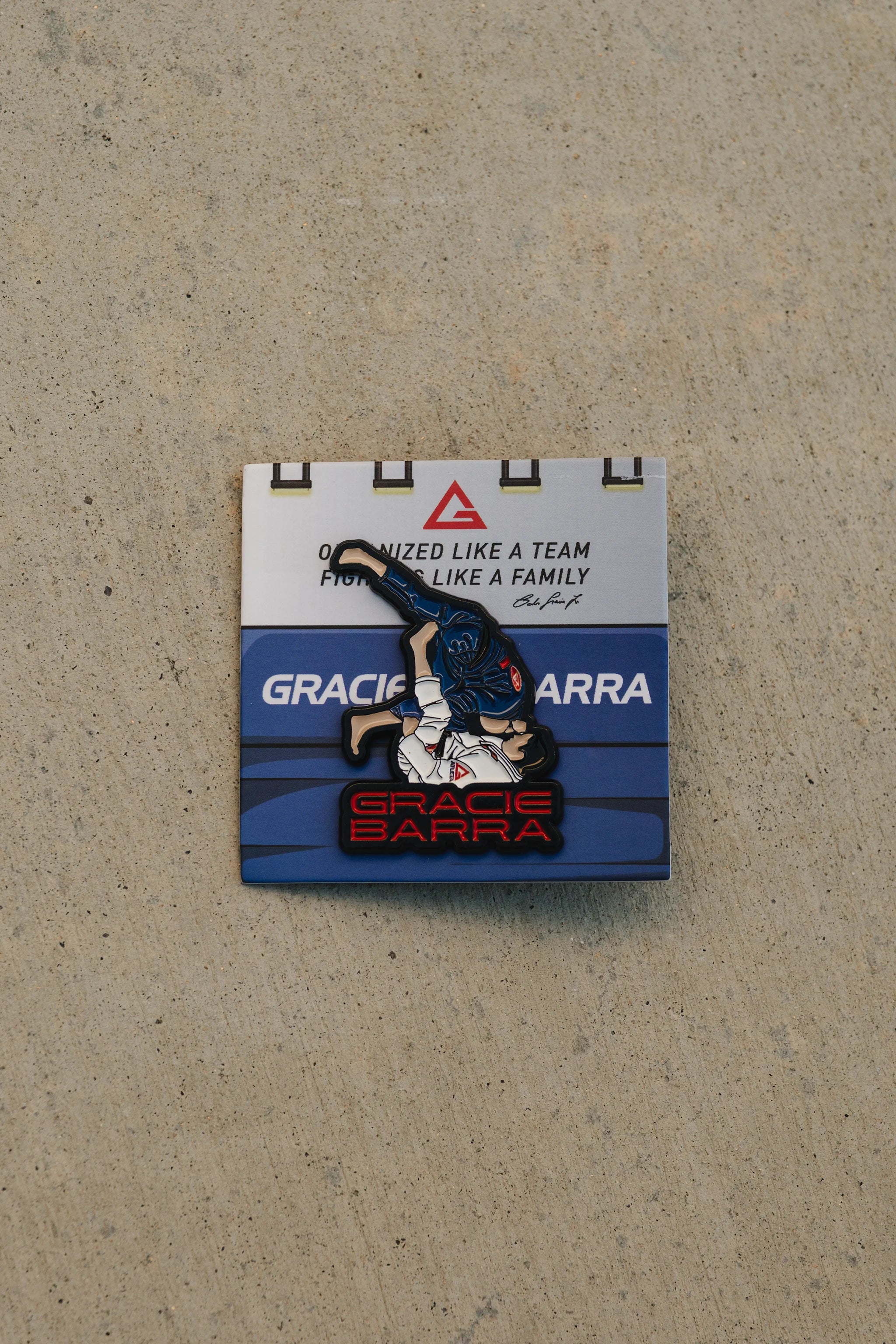 Enamel sweep-position pin displayed on a Gracie Barra backing card against a concrete background.