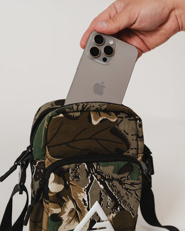 GB Tactical Cross Body Pack in camouflage with white Legacy G logo, shown with a phone for size reference.