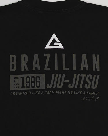 Close-up of Tactical Men’s Tee in black with Legacy G logo and “Brazilian Jiu-Jitsu Est. 1986” text design in gray, displayed on a light gray background.