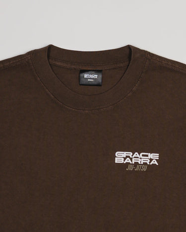 Close-up of chest area on Tactical Men’s Tee in dark brown with white Gracie Barra Jiu-Jitsu logo, displayed on a light gray background.
