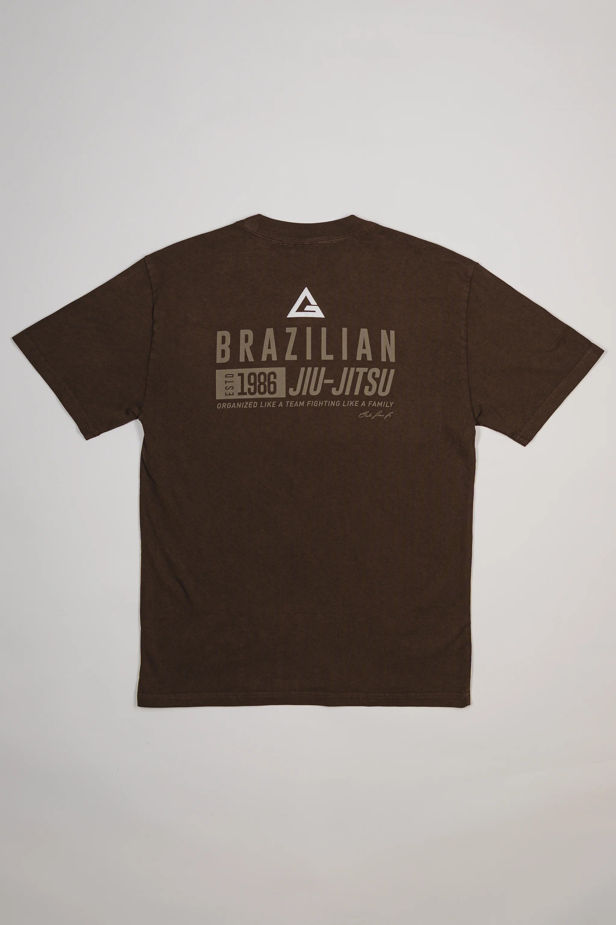Back view of Tactical Men’s Tee in dark brown featuring Legacy G logo above bold “Brazilian Jiu-Jitsu” text with 1986 heritage graphic, displayed on a light gray background.