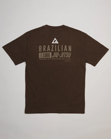Back view of Tactical Men’s Tee in dark brown featuring Legacy G logo above bold “Brazilian Jiu-Jitsu” text with 1986 heritage graphic, displayed on a light gray background.