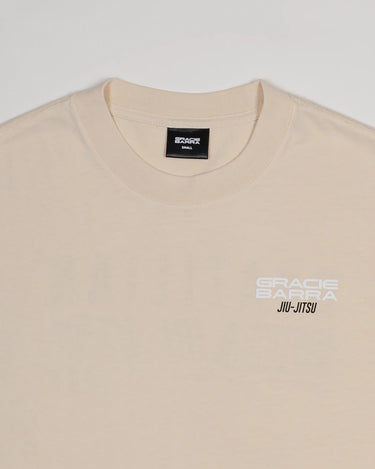 Close-up of chest area on Tactical Men’s Tee in natural beige with white Gracie Barra Jiu-Jitsu logo, displayed on a light gray background.