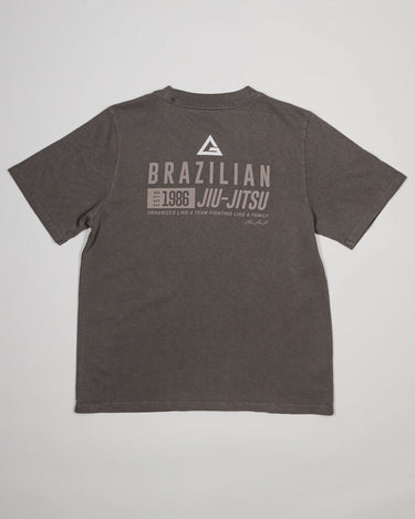 Back view of Tactical Women’s Tee in gray with Legacy G logo and “Brazilian Jiu-Jitsu” text printed across the upper back, displayed on a light gray background.