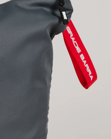Close-up of grey GB Tech Wash Bag with black zipper and red Gracie Barra branded drawcord handle.