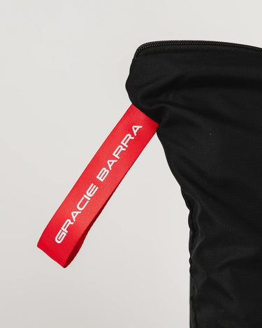 Close-up of GB Tech Wash Bag in black with red pull tab featuring Gracie Barra branding, part of dual-zip odor-control design.