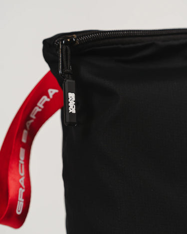 Close-up of GB Tech Wash Bag in black ripstop with dual-zip construction, featuring a red Gracie Barra handle strap and branded zipper pull