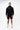 Technical Flow Mens Hoodie in black, full-length front view on standing model, hood down with tonal Legacy G chest logo and front pouch pocket.