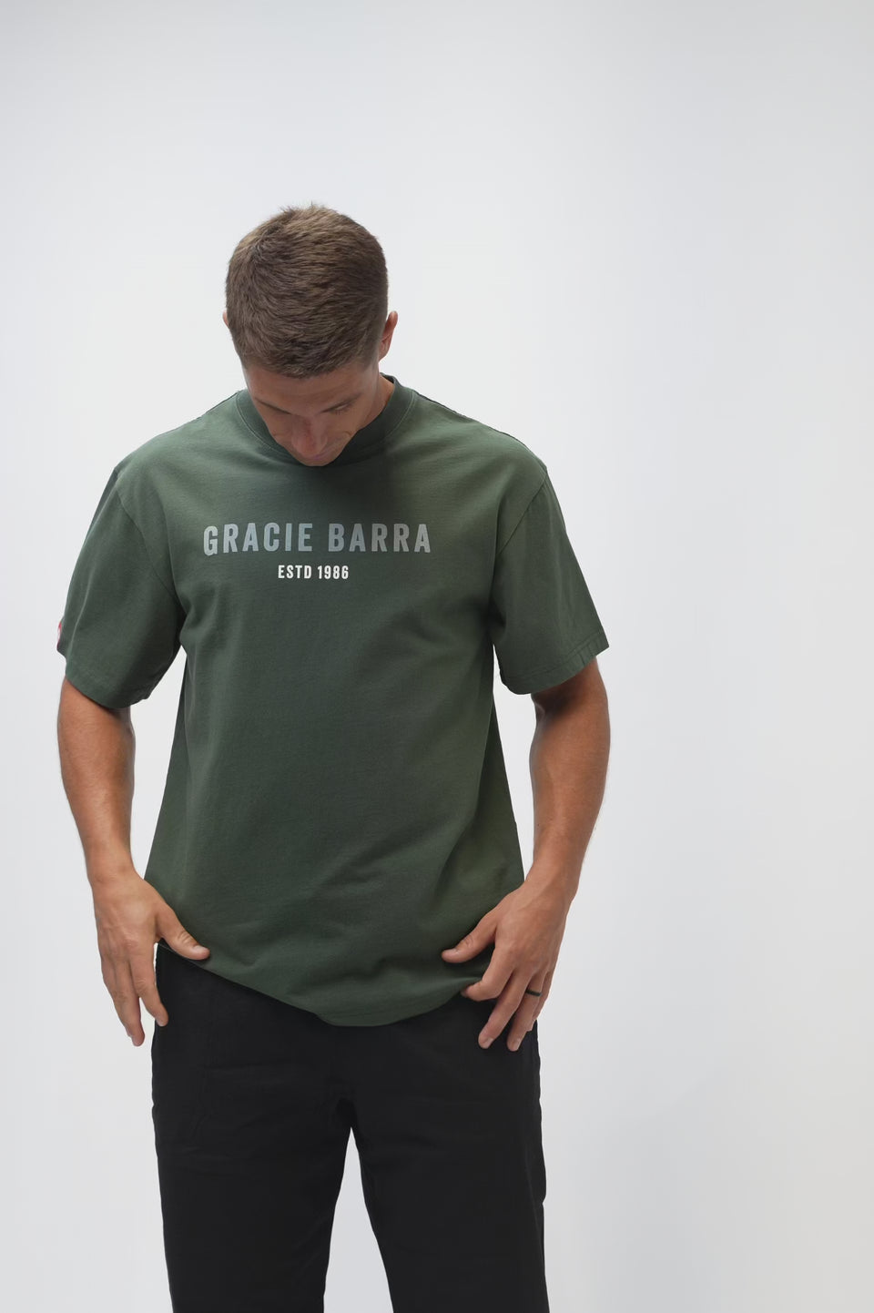 Rio Roots Mens Tee in Forest Green — video of model turning to show the Gracie Barra Estd 1986 front graphic, red sleeve tag, and archival back photo.