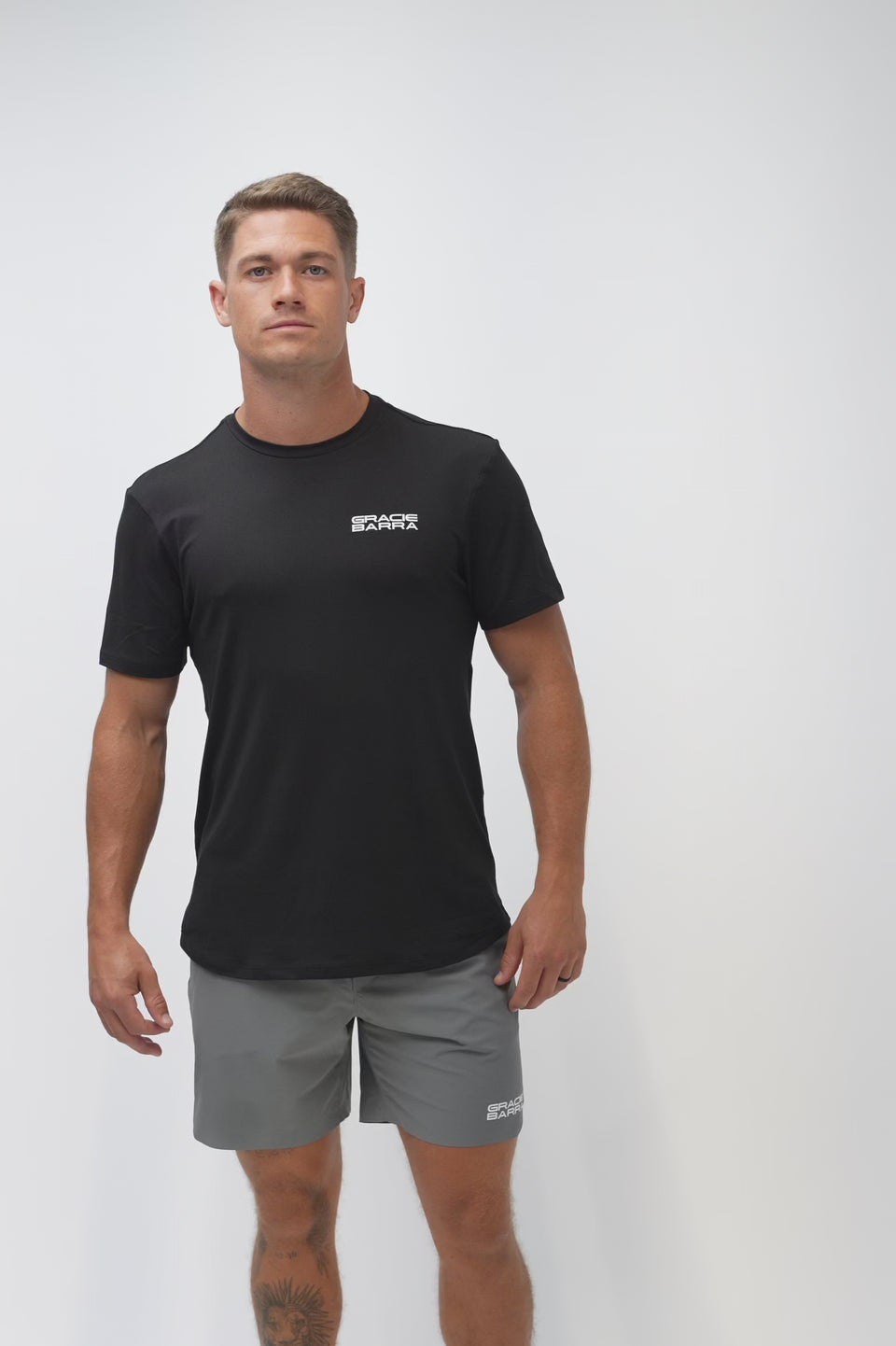 Video of a male model turning to show the front, back, and side of the Flow Men's Tech Tee in black and Frame Men's Short in dark grey