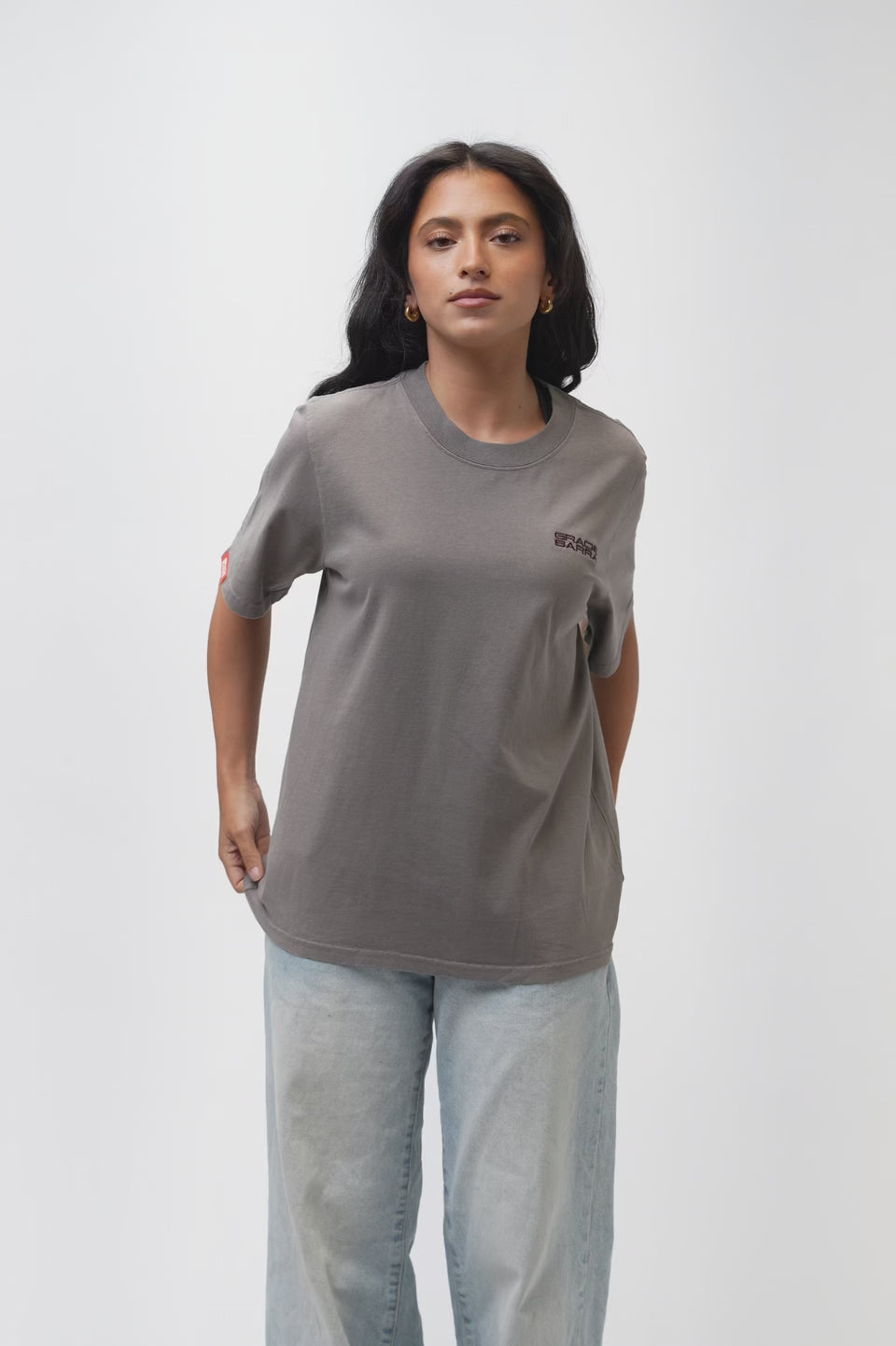 Emblem Womens Tee, grey — 360° turnaround video showing the relaxed oversized fit front to back, with burgundy embroidered Gracie Barra chest emblem and the Legacy G triangle logo above a "JIU-JITSU" wordmark on the back.